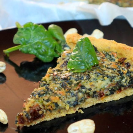 Spinach tart on a plate with spinach and cashews