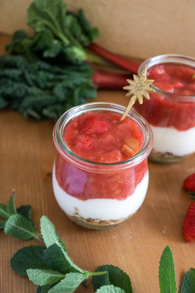 Dessert mit Erdbeer-Rhabarber-Kompott 
angerichtet auf einem Tisch mit Gemüsedeko im Hintergrund